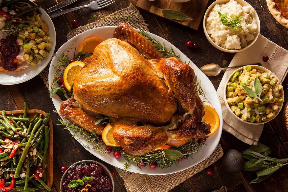 Thanksgiving Dinner with beans, stuffing, and potatoes with a large turkey in the middle of the image.